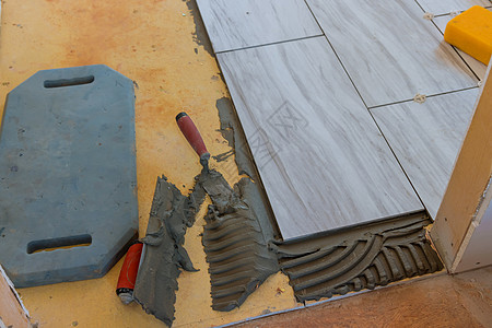 在修理翻新时安装地板瓷砖的Tiler建筑工人图片