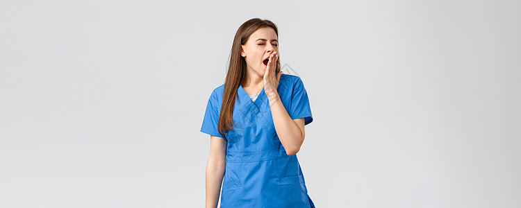 医护人员 预防病毒 保险和医学概念 疲惫的年轻女护士在医院上夜班 打哈欠 用手掌捂住嘴巴 感到困倦 精力不足管子口罩学院防护服实图片