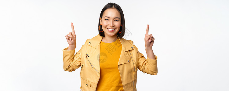 充满激情的亚裔女孩举起手来 在顶部张贴广告 微笑快乐 展示宣传提议或标语 站在白背景上站立女朋友销售情感促销购物大学标识企业家办图片