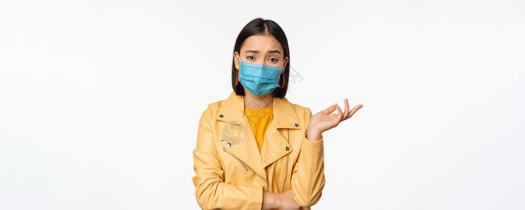 戴着医用面罩的困惑的亚洲女性 看起来毫无头绪 困惑 戴着医用面罩 站在白色的工作室背景上商业情感女士购物成人企业家微笑办公室情绪图片