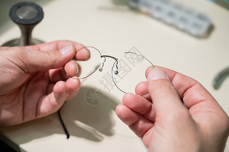 修理一个破碎的眼镜框的人 把眼科医生的手闭上图片