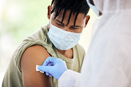 清洁注射部位 在注射 covid 19 疫苗之前 一位面目全非的医生正在清洁一位英俊的年轻男性患者的注射部位图片