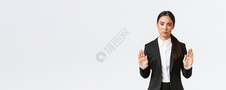 严肃的亚裔女经理 穿着黑色西装的女商务人士停止行动 禁止或限制某事 举起双手禁止手势 说不或足够 白色背景团队快乐办公室商业经理图片
