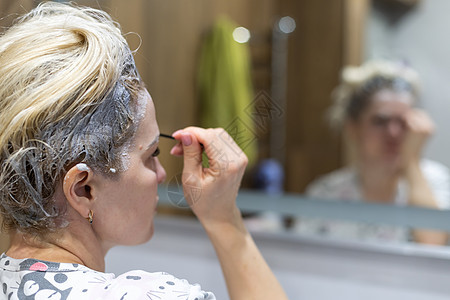 女人自己染头发和眉毛程序刷子女士镊子指甲花沙龙细绳宏观女性眼睛图片