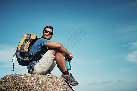 看看这美丽的景象 一个无忧无虑的年轻人 白天在山上徒步旅行时短暂休息的肖像图片