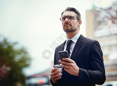 一名成熟的商务人士在城市外用手机发短信的照片 当时他正忙着搬家图片