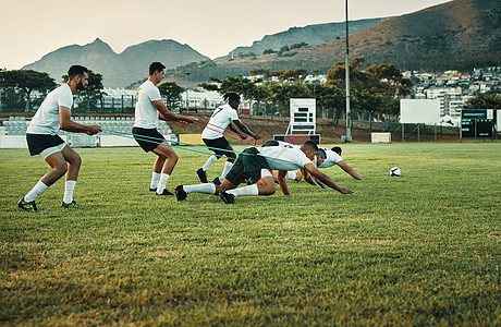 一队年轻的橄榄球运动员白天在野外用乐队训练 拍完全的镜头 校对图片