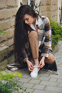 穿着长外套 米色裤子和白衬衫的年轻漂亮时装女郎近身肖像 女士们在城市街道上摆姿势头发街道鞋带冒充运动鞋城市奢华女士达人女孩图片