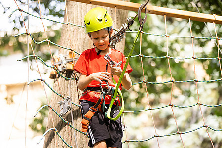 可爱的学校男孩享受阳光明媚的日子 在攀山冒险活动公园运动操场喜悦森林闲暇自由挑战绳索勇气力量图片