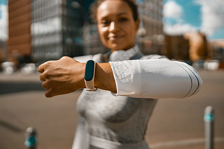 利用健身智能手表在阳光明日户外慢跑时使用运动手表的女运动员图片