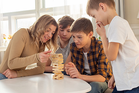 快乐的家庭 在房间里玩一个由木形矩形区块组成的棋盘游戏图片
