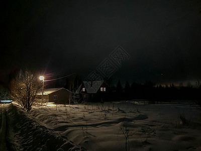冬季夜晚俄罗斯村庄 一条有雪和光的公路 从房屋窗户上走出来建筑国家旅行小屋降雪森林旅游季节木头夜空图片