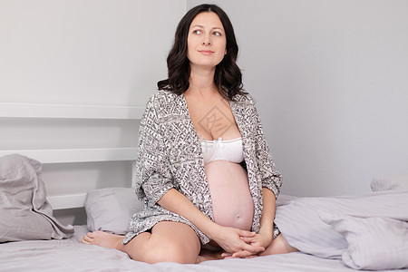 快乐漂亮的女人享受怀孕 母亲是期待父母 可爱的大肚子 怀孕的黑发在明亮的房间里一部分头发母性身体休息女士客厅肚子孩子生活方式图片