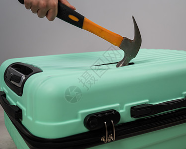 一个女人用锤子敲一个手提箱 在白色背景上破坏蓝色假期报告游客行李失败保险旅游塑料图片