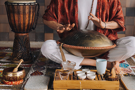 在茶叶仪式期间 用猎户座舌鼓敲响一个演奏现代乐器的人的手贴近旋律民谣精神治疗振动谐振游戏音乐家语言韵律图片