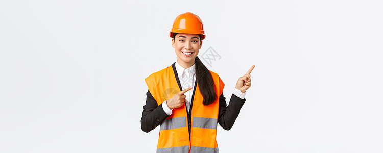 建筑 施工和工业概念 身着安全头盔和反光服的微笑亚洲女工程师展示物品 右指 女售货员向客户介绍房产装修商务建筑师快乐经理员工人士图片