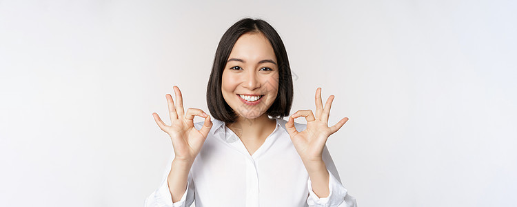 特写亚洲女孩的头像 表现出好的 好的手势和满意的微笑 推荐 高兴 赞美和恭维 白色背景管理人员办公室女士公司工作室成人商业冒充人图片
