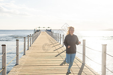 女人在红海的浮艇桥上奔跑运动女孩蓝色饮食闲暇黑发自由太阳幸福地平线图片