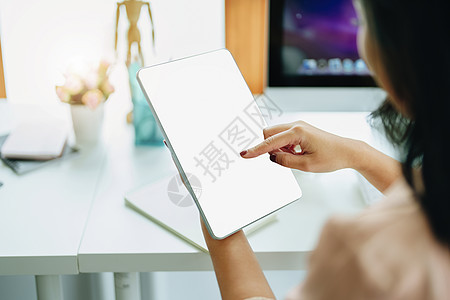 年轻女性使用家庭平板电脑工作以避免在公司工作时感染冠状病毒的风险 平板电脑屏幕上的空白区域可以插入文本桌子工具桌面键盘小样展示商图片