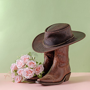 牛仔靴鞋鞋 帽子和花束花花 绿色背景图片