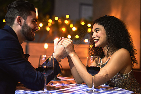 我们会永远在一起 拍摄一对欢快的年轻夫妇在晚上烛光晚餐约会时手牵着手看着对方的眼睛图片