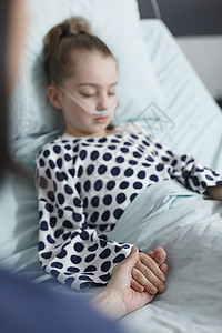 慈爱的母亲握着住院生病女儿的手 躺在儿科诊所的床上放松图片