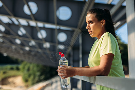 锻炼后用瓶水喝的疲劳妇女图片