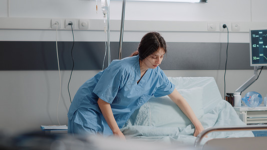 担任在医院病房准备床铺的护士的妇女图片