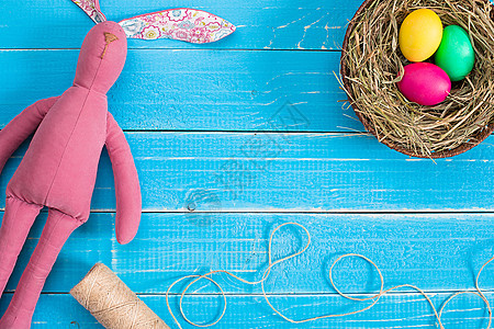 粉色蓝色系兔子巢中的复活节鸡蛋和蓝生锈木木木板上的兔子背景