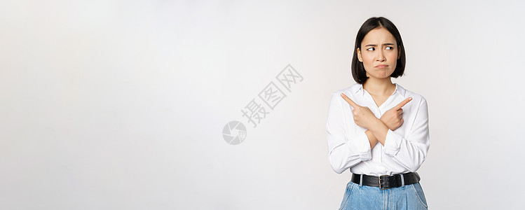 优柔寡断的亚洲女性侧身指指点点 指指点点 看起来一头雾水 对选择感到困惑 站在白色背景上成人员工技术手臂管理人员标识商务公司办公图片