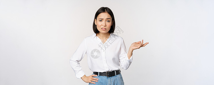 困惑的亚洲女性的画像 问什么 你的问题手势是什么 困惑地凝视着 无能为力 恼怒 站在白色背景上老板广告女士售货员办公室管理人员商图片