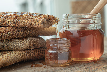 从玻璃罐上的新鲜蜂窝里滴的美味蜂蜜 和老木制桌子上的伍德蜂蜜配方棒标签健康饮食营养品金子香气液体草药美食食物葡萄糖图片