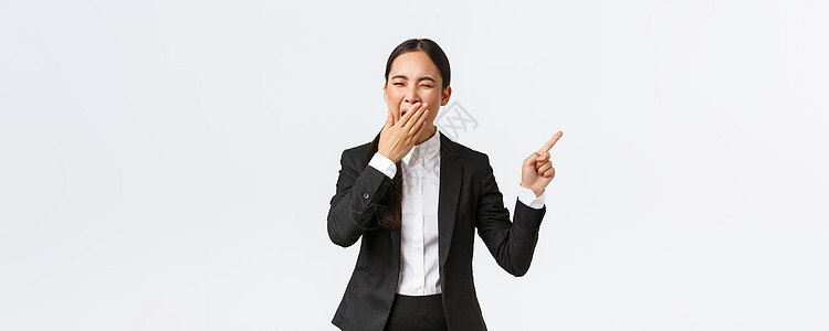 疲惫的女办公室经理 穿着西装的企业家用手指着右手打哈欠 无聊或疲惫的亚洲女商务人士工作到很晚 展示项目 站在白色背景员工工程师企图片