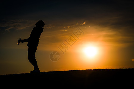 黄昏时站在山丘上的男人的休眠三鹰背景男性阴影爬坡草原例子日落天空太阳图片