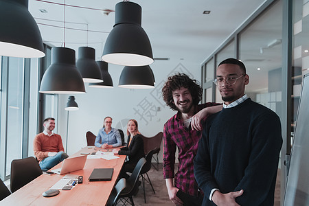 现代办公室中两个快乐的千禧一代男性企业主的肖像 两个商务人士微笑着看着相机 忙碌的多元化团队在后台工作 领导概念 爆头房间职场演图片