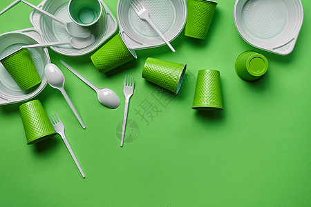 在绿色背景的白色塑料一次性餐具与拷贝空间 野餐用具的概念 顶视图 选择性的焦点 特写服务环境桌子早餐盘子外卖用具工具烹饪炙烤图片