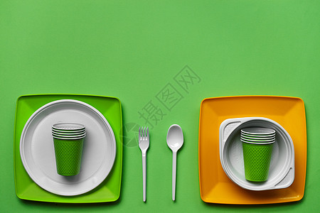 在绿色背景的五颜六色的塑料一次性餐具与拷贝空间 野餐用具的概念 顶视图 选择性的焦点 特写食物派对咖啡店刀具桌子商品厨具厨房餐饮图片