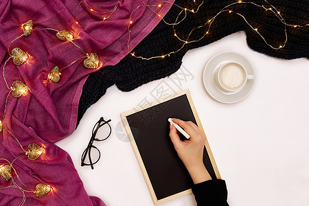女孩手写在白色表面有咖啡杯和其他物品的小黑木板上 上面是女孩手的顶部视图铅笔商业办公室杯子手臂学习笔记本记事本学生商务图片