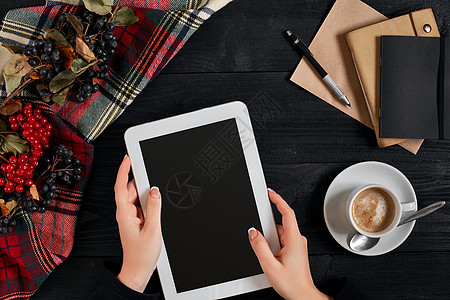 妇女手握平板板 黑屏在桌子上方 一杯咖啡和智能咖啡女士互联网药片办公室屏幕工具软垫技术手机手指图片