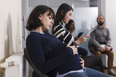 怀孕的招聘人员 在创业企业办公室里拉着手肚子等待工作图片
