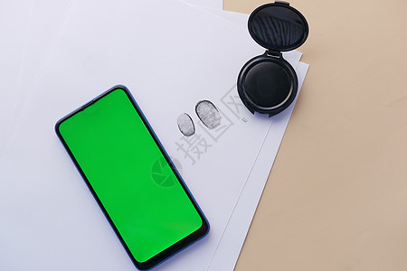 纸上和智能手机上不同的黑色指纹 带有绿屏屏幕图片