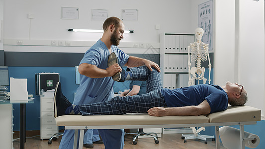 使用腿的治疗师提高锻炼以拉伸肌肉和断裂骨头图片