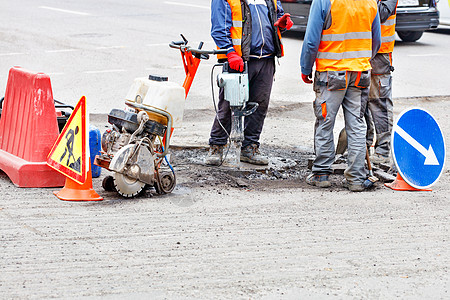一组路务工人配备了电动大锤 煤气切割机 铲子和刷子 他们讨论了道路部分维修计划图片