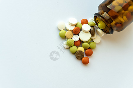 医学和药丸 在白色背景特写镜头的多色药物 有里面药片的棕色玻璃瓶在白色背景 从倒置的罐子中溢出到白色表面的多色药片健康疾病卫生胶图片