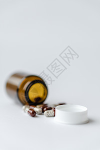 医学和药丸 在白色背景特写镜头的药物 有里面胶囊的棕色玻璃桶在白色背景 从倒置的罐子里溢出的药丸落在白色的表面上医院健康药剂团体图片