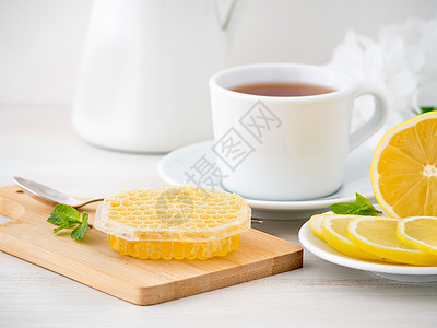 白杯加茶 柠檬片和蜂蜜在白色木制桌椅上的蜂窝中的蜂蜜食物草本植物叶子勺子香气芳香饮料药品玻璃桌子图片
