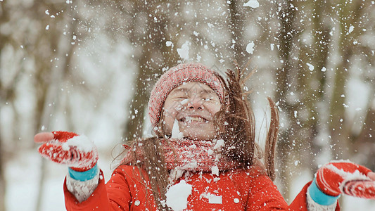 年轻女学生喜悦地扔雪球 倒下时用手掌打碎它 快乐的情感 在森林里自然界中的冬季乐趣空气公园木头女士笑声闲暇青少年手套棕榈帽子图片