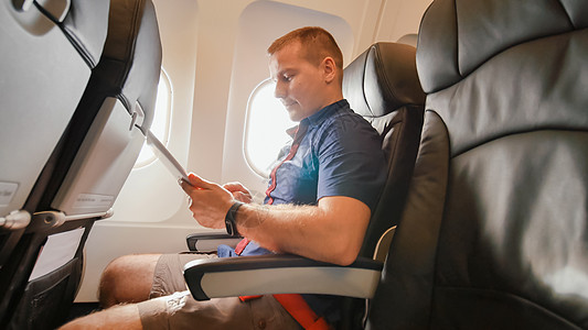 飞机上的一名年轻游客在离开之前与平板电脑一起工作图片