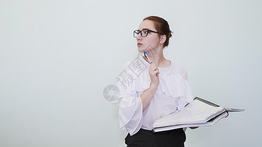 戴眼镜的女学生用笔记描绘了一个成功的女孩 一个学生描绘了一个遐想 问题的解决方案学习知识黑发头发学校衬衫女性人士瞳孔图书馆图片