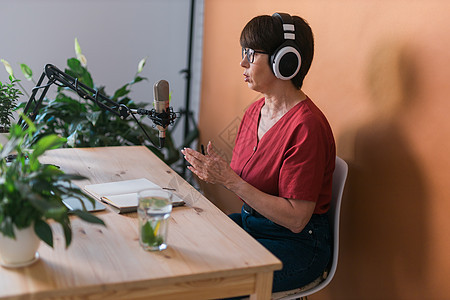 中年女电台主持人为在线节目制作播客录音  广播和 DJ 概念打碟机工作室公告娱乐笔记本商业扬声器耳机嗓音播音员图片